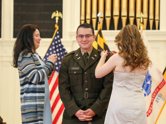 Photo of Jack Buckley at Commissioning with family adding pins to his uniform.