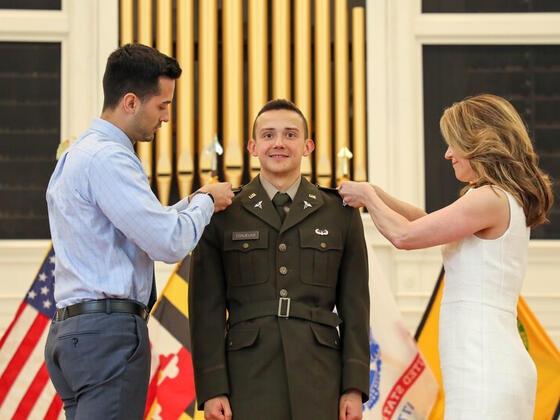 Jack Conjelko at Commissioning with his family adding pins to his uniform.