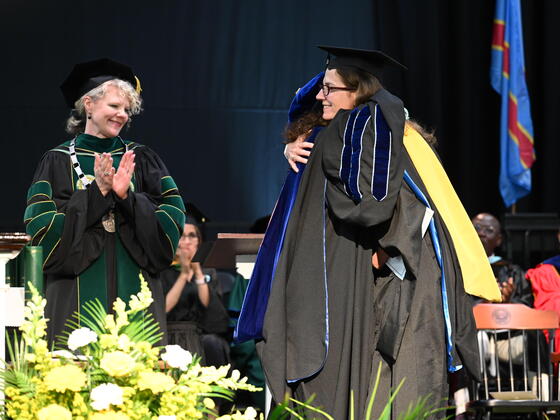 Kerry Duvall hugging Wendy Morris with Julia Jasken looking on at Commencement.