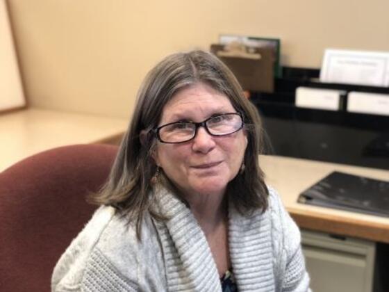 Susan Flanders smiles at her desk in the Graduate and Professional Studies Office