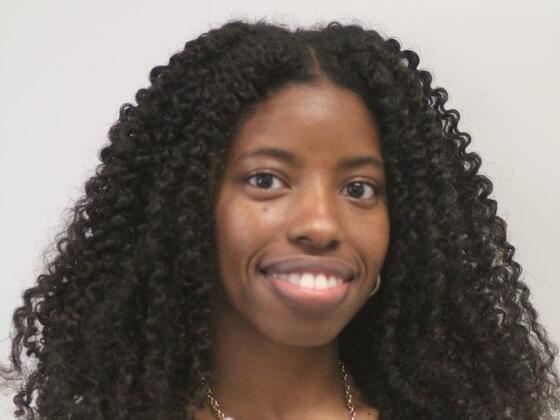 Headshot of Alisha Swann in a pink shirt on a grey background.