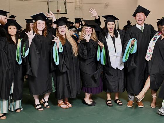 A group photo of graduates of the Deaf Education program wearing their caps and gowns and laughing.