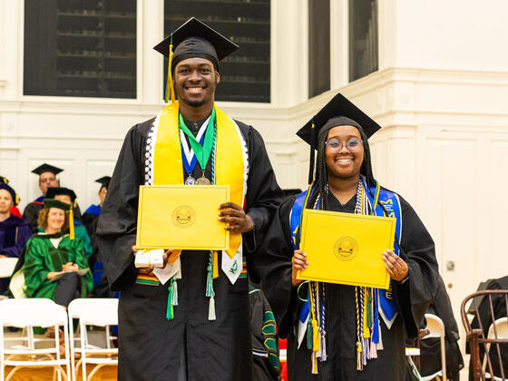 students in graduation regalia pose with awards