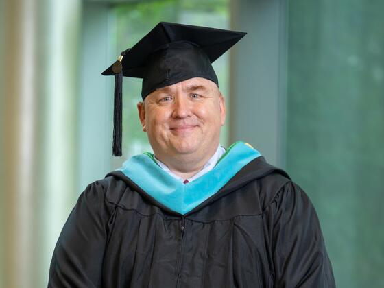 Headshot of Brian Fleming wearing black graduation regalia. 