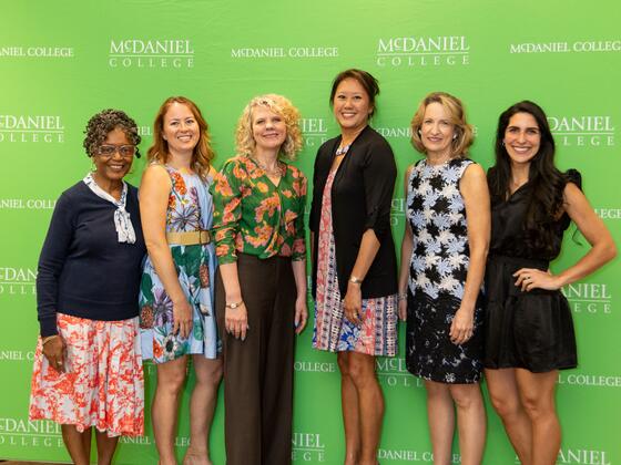 Six women stand together smiling.