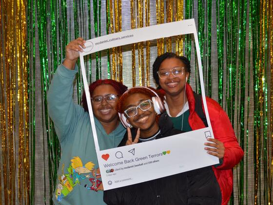 Three students smile through a prop that looks like an Instagram border and reads "Welcome back Green Terrors" at the bottom.