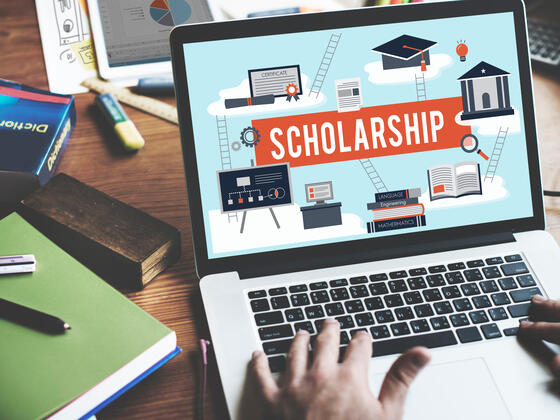 A laptop is displaying a graphic that says "Scholarship"