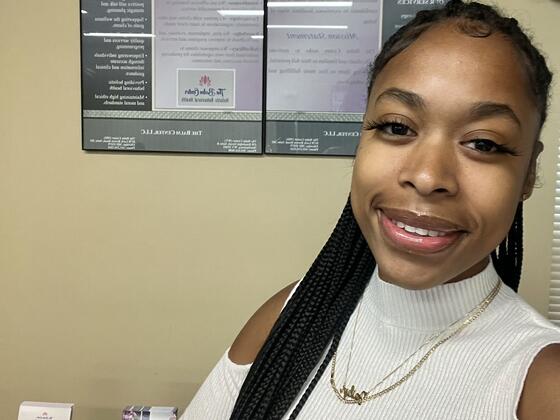A Black woman in a white sweater smiling.