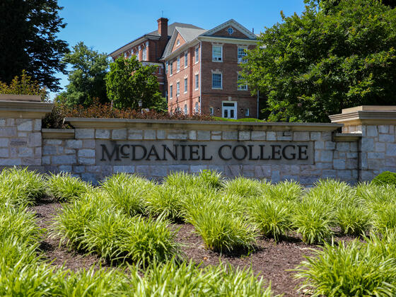 brick entry way sign that says McDaniel College with campus buildings in the background
