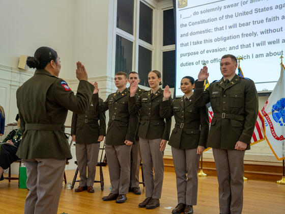 Four cadets in a row hold up a hand while reciting their oath at Commissioning.