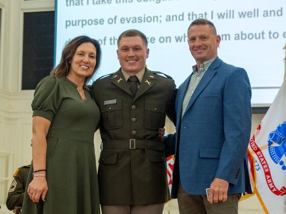 Justin Long smiles in uniform with his parents at Commissioning.