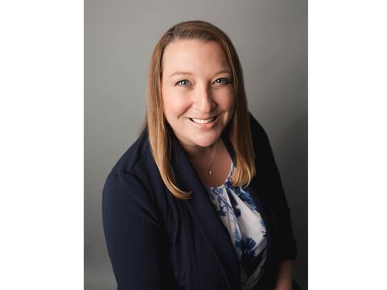 Headshot of Kristi Yowell in a black suit jacket.