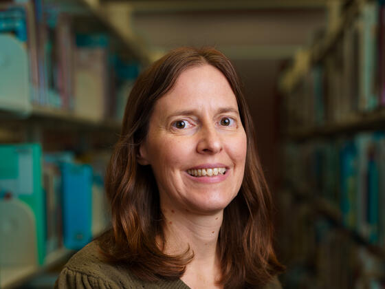 Lisa Buckler wears a brown shirt and smiles in the McDaniel College library.