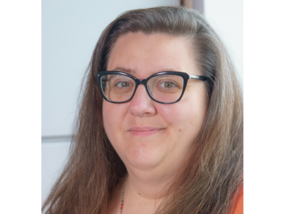 A woman with long, brown hair and glasses.