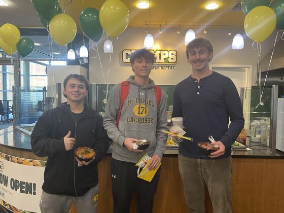 3 students pose in front of the newly opened Champs dining location in Gill Center