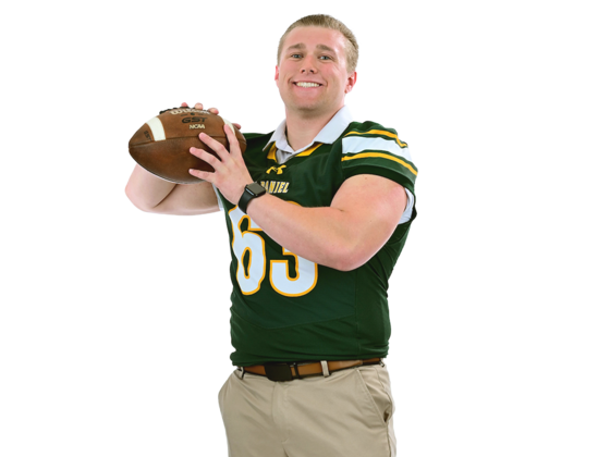 A male student wearing a football jersey prepares to throw a football.