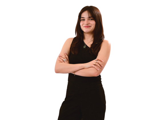 A female student wearing all black stands with her arms crossed.