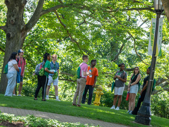 group of students stand in a circle with trees in the background