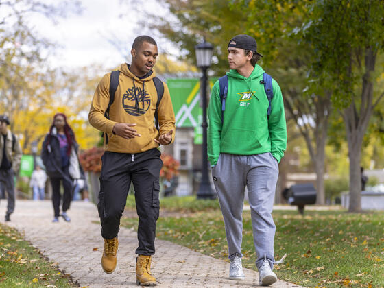 Two students chat and walk on the McDaniel campus.