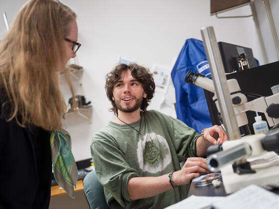 A male student shows his work with a microscope in the lab.
