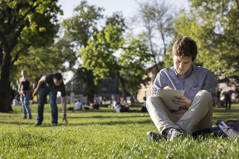 Student writing in notebook outside of Budapest campus.