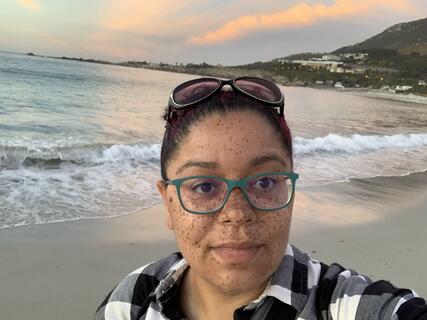 Alumni Jessica Watson in front of a beach sunset in Cape Town, South Africa.