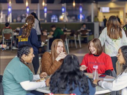 A group of students sits at a table in the McDaniel College dinging hall. 