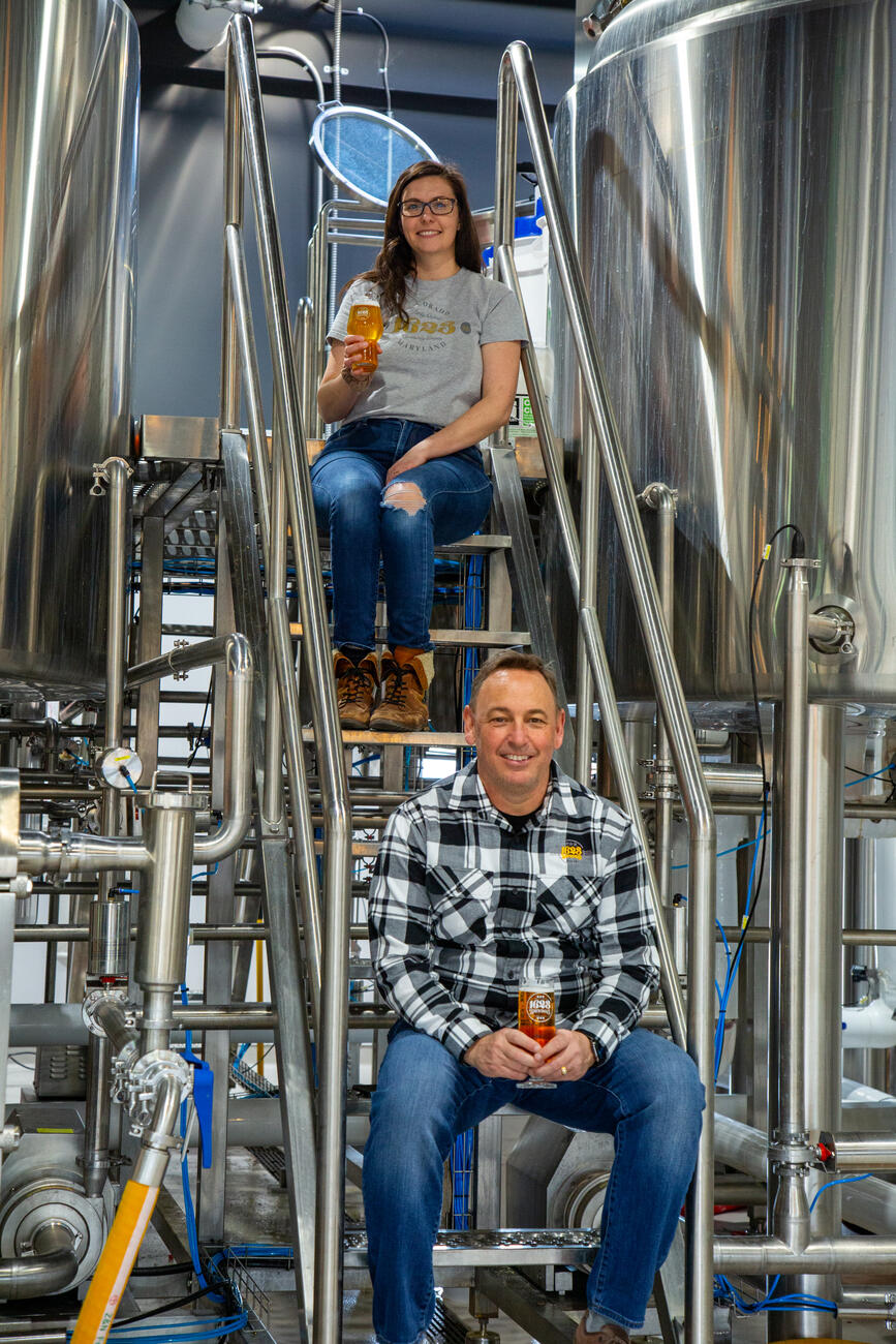 Mike McKelvin and a brewery employee sit by the brewing vats.