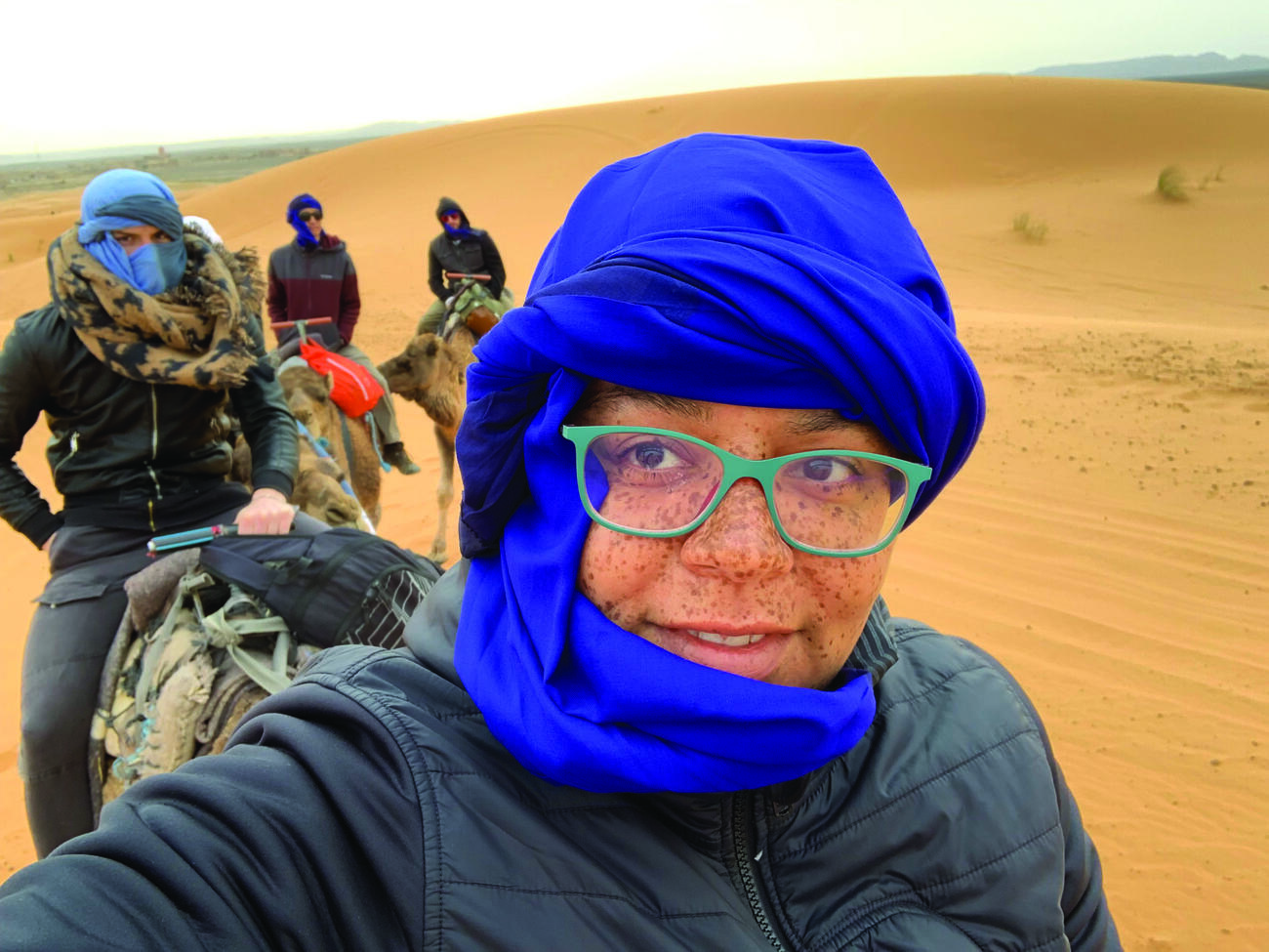 Alumni Jessica Watson riding a camel in the desert. 