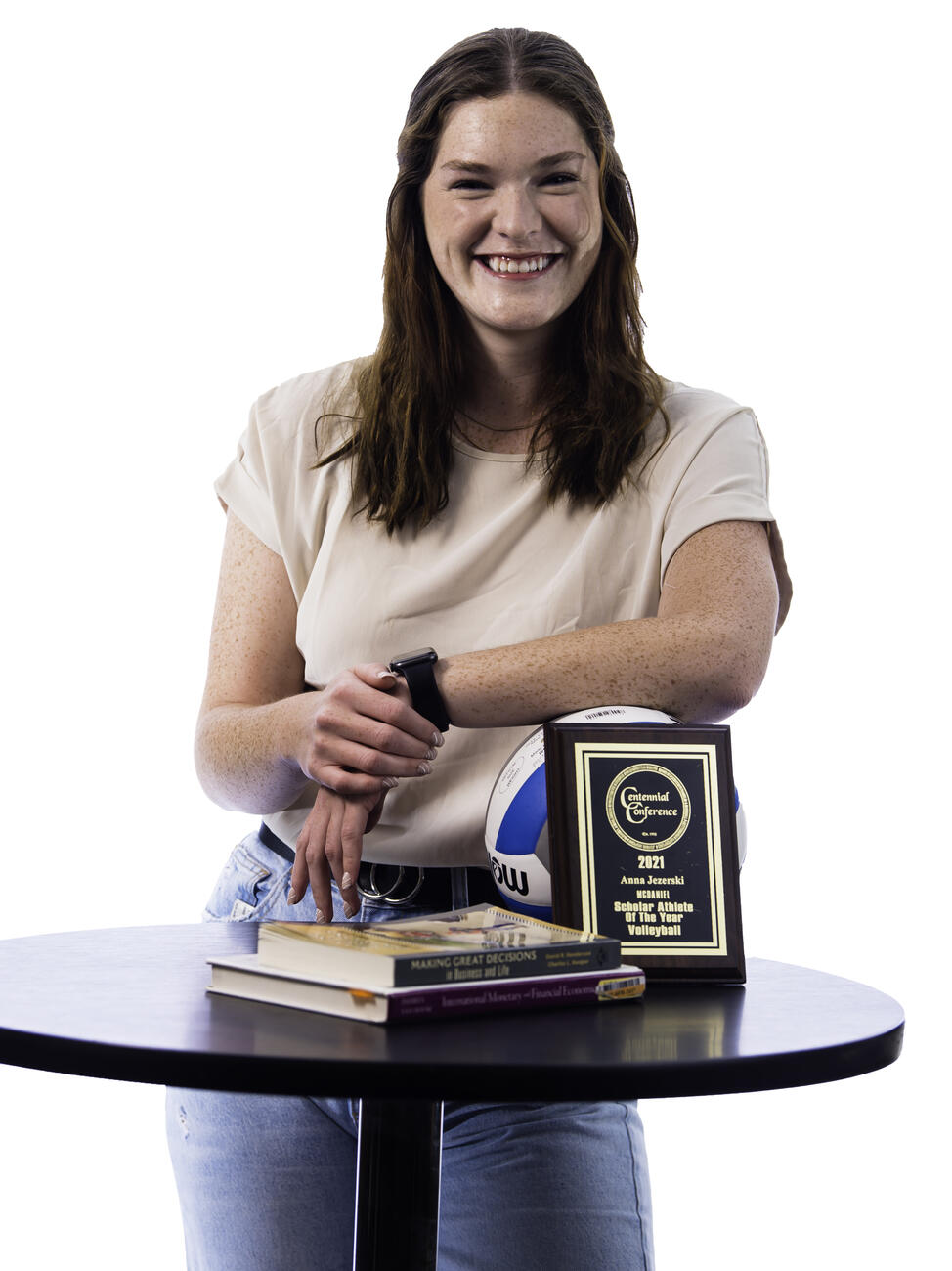 Anna Jezerski poses by a table holding a plaque and some books.
