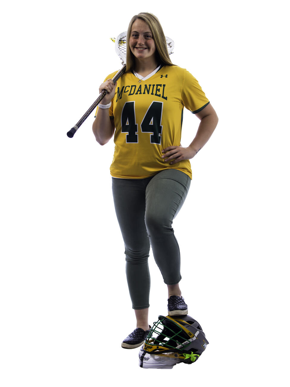 Hannah Miller poses with a lacrosse stick over her shoulder and her foot on a helmet.