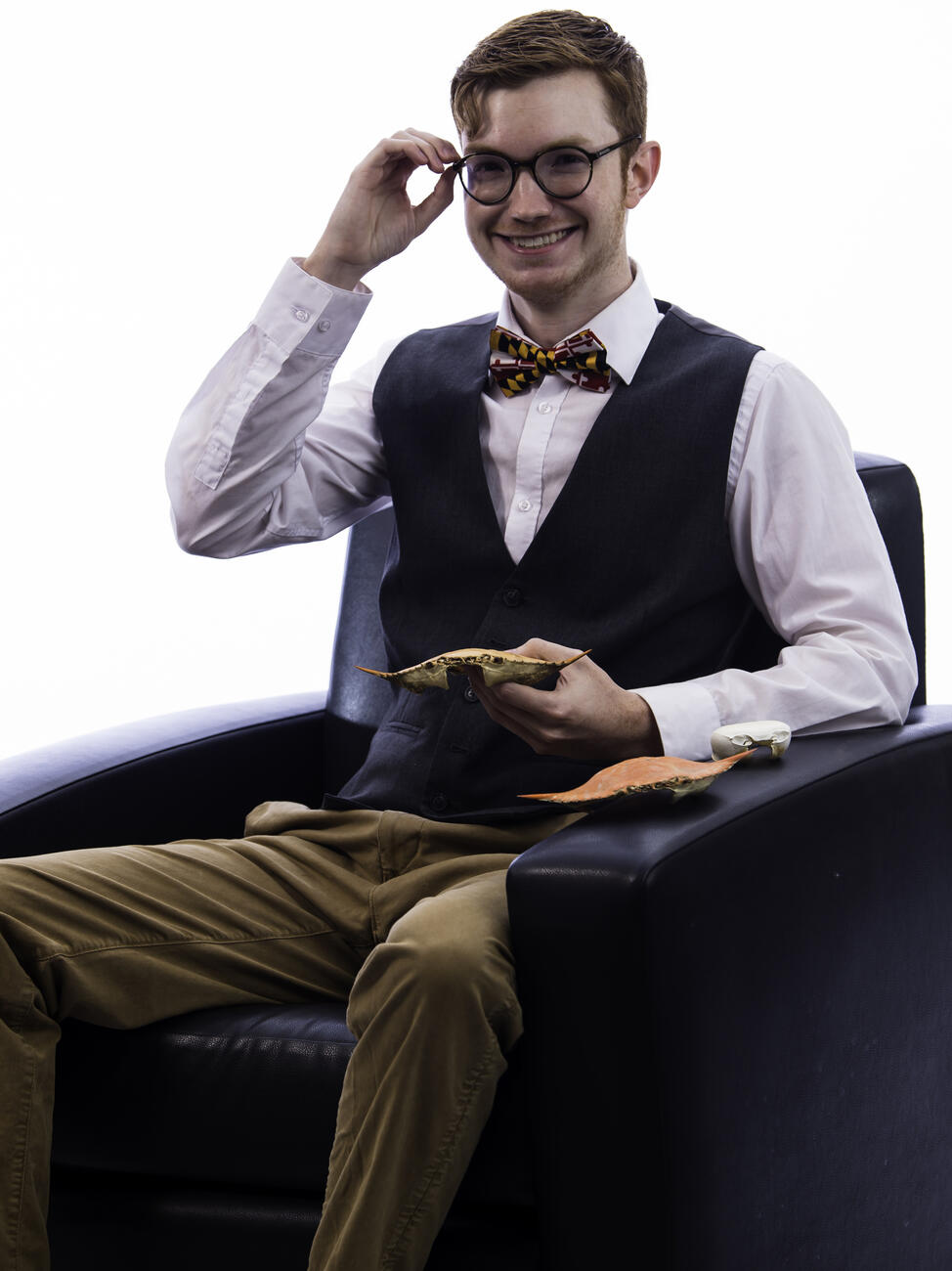 Zach Drechsler seated in a chair while holding a crab shell.