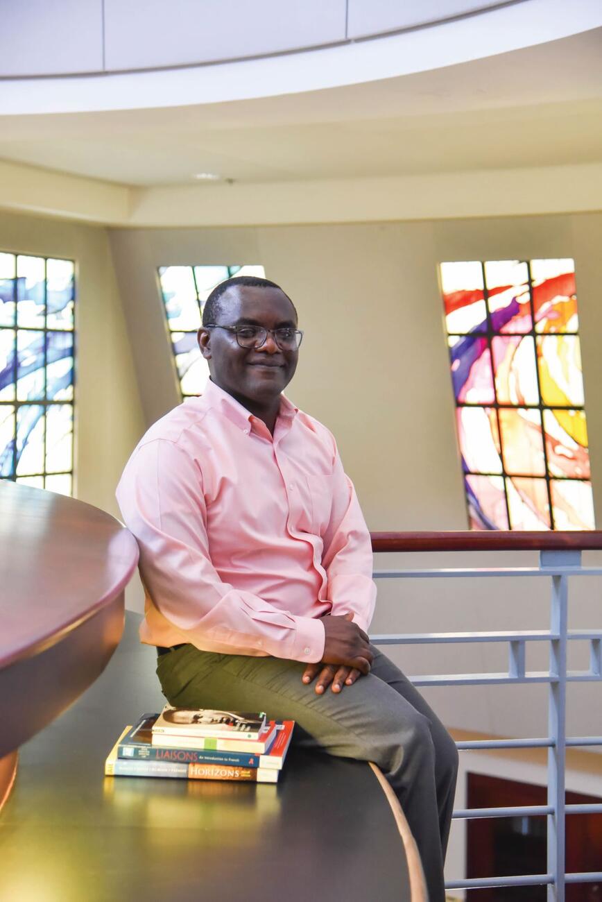 Photo of professor Gerard Keubeung seated in the library next to some books.