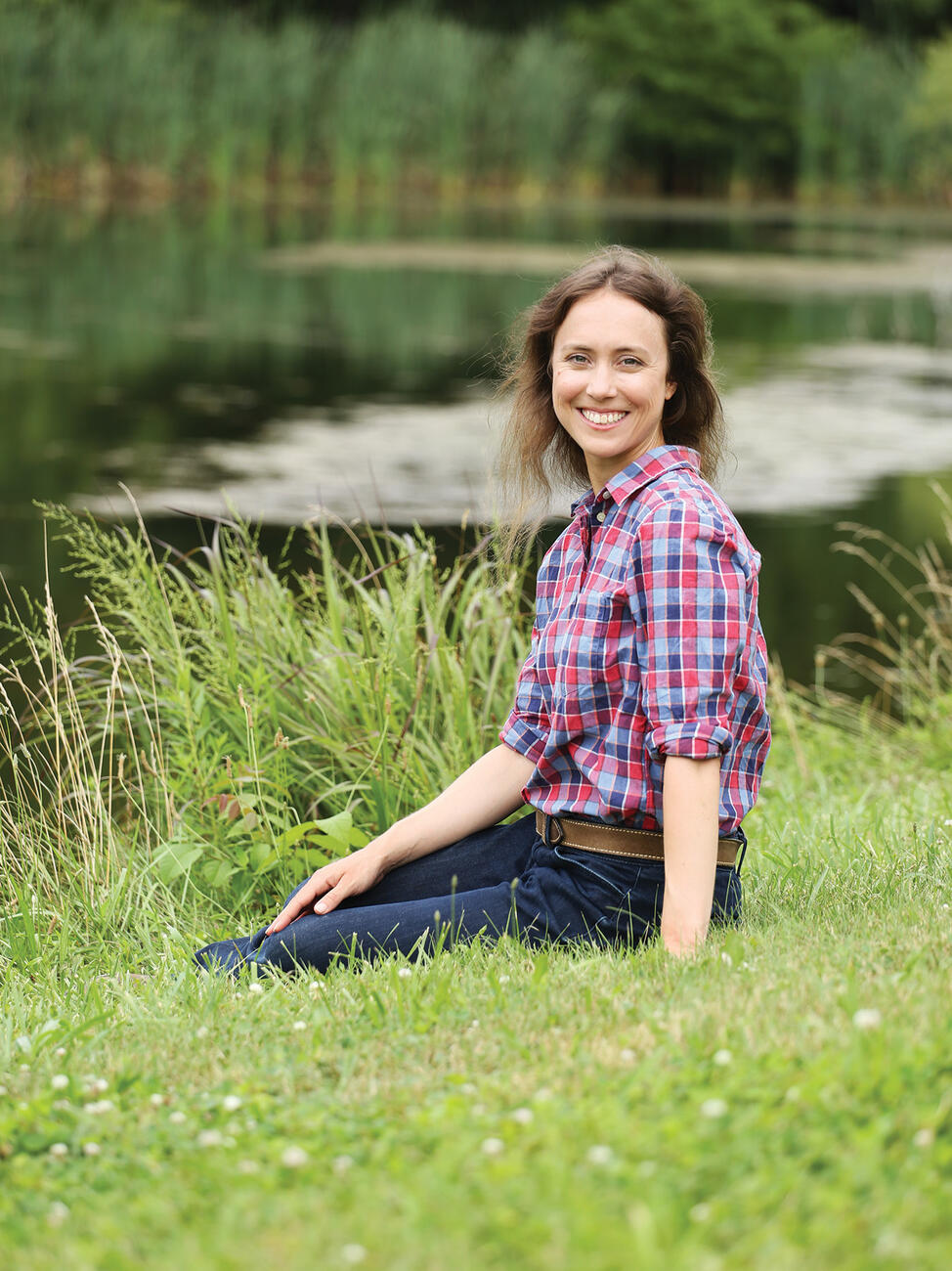 Photo of professor Margaret Christie sitting on the bank of a lake. 