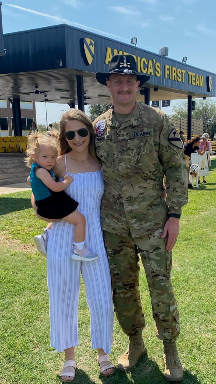 Zach Nibbelink in Army uniform with his wife and daughter.