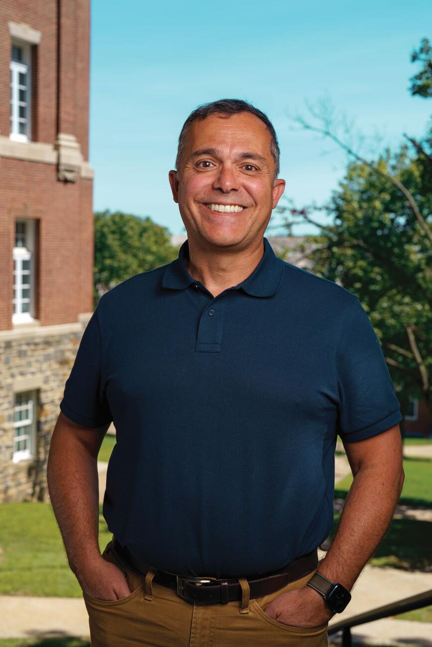 Photo of Adriano Lime e Silva in a blue button up smiling outside on campus.