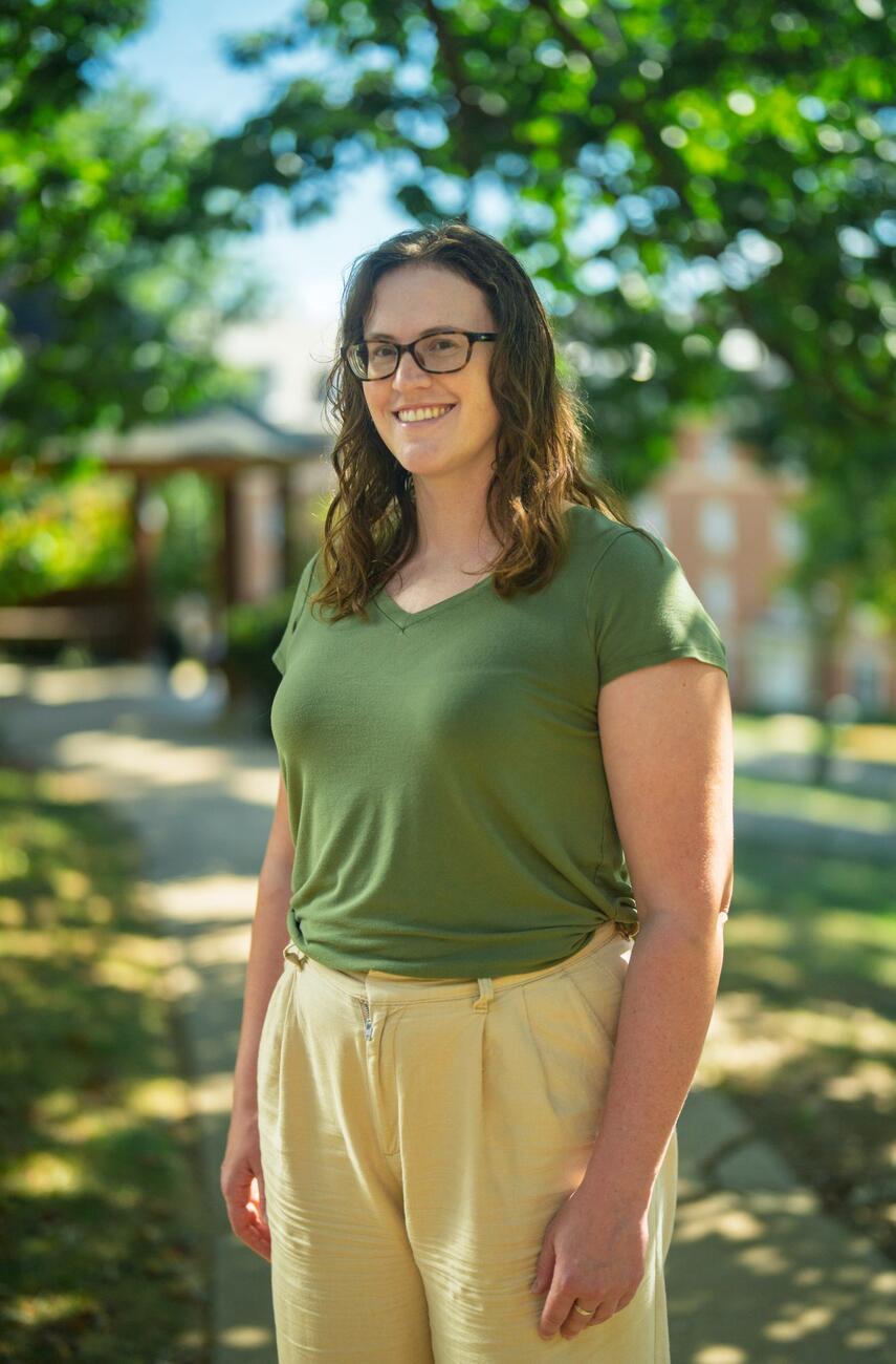 Christine Conte stands outside in front of a gazebo while wearing a green shirt and tan pants.