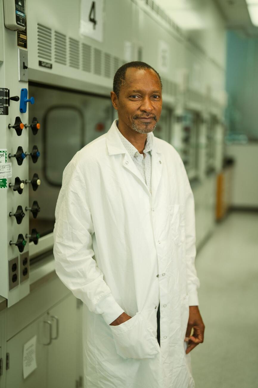 Katana Ngala stands in a college lab wearing a white lab coat.