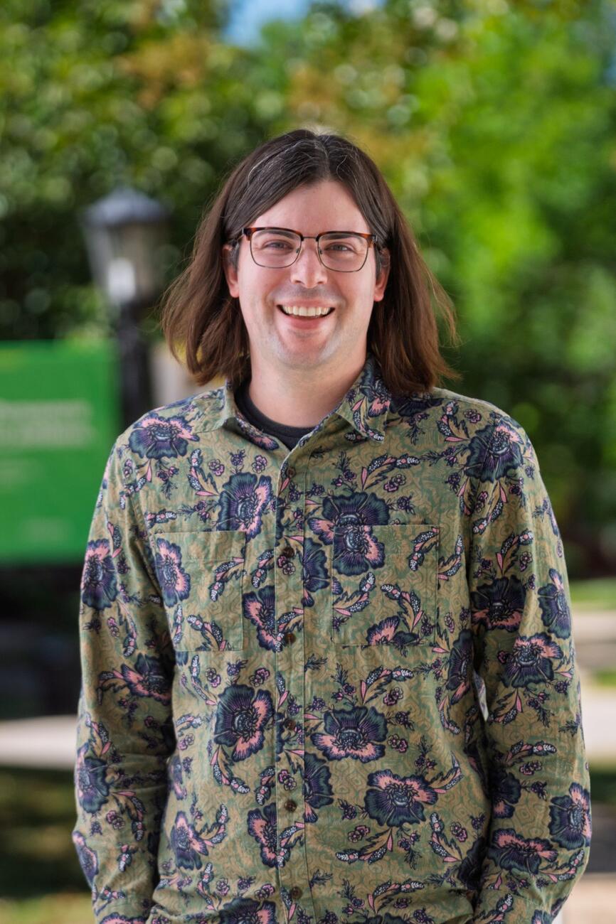 Timothy Swartz stands outside wearing a green paisley shirt.