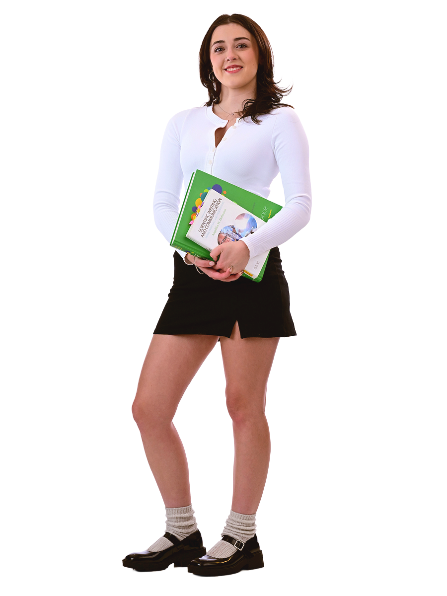 A female student stands holding books.