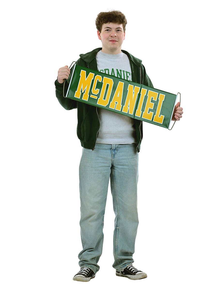 A male student stands holding a McDaniel banner.