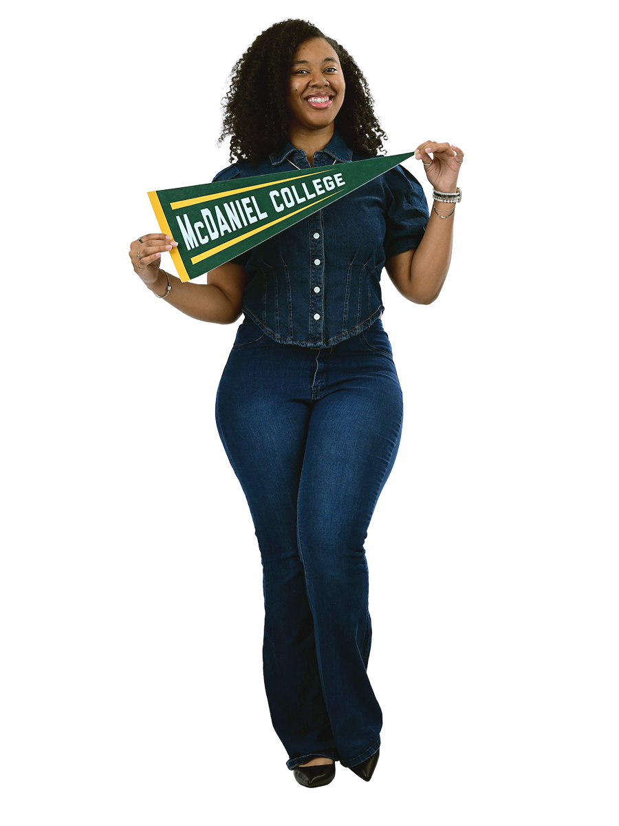 A female student wearing a denim outfit poses with a McDaniel College pennant.