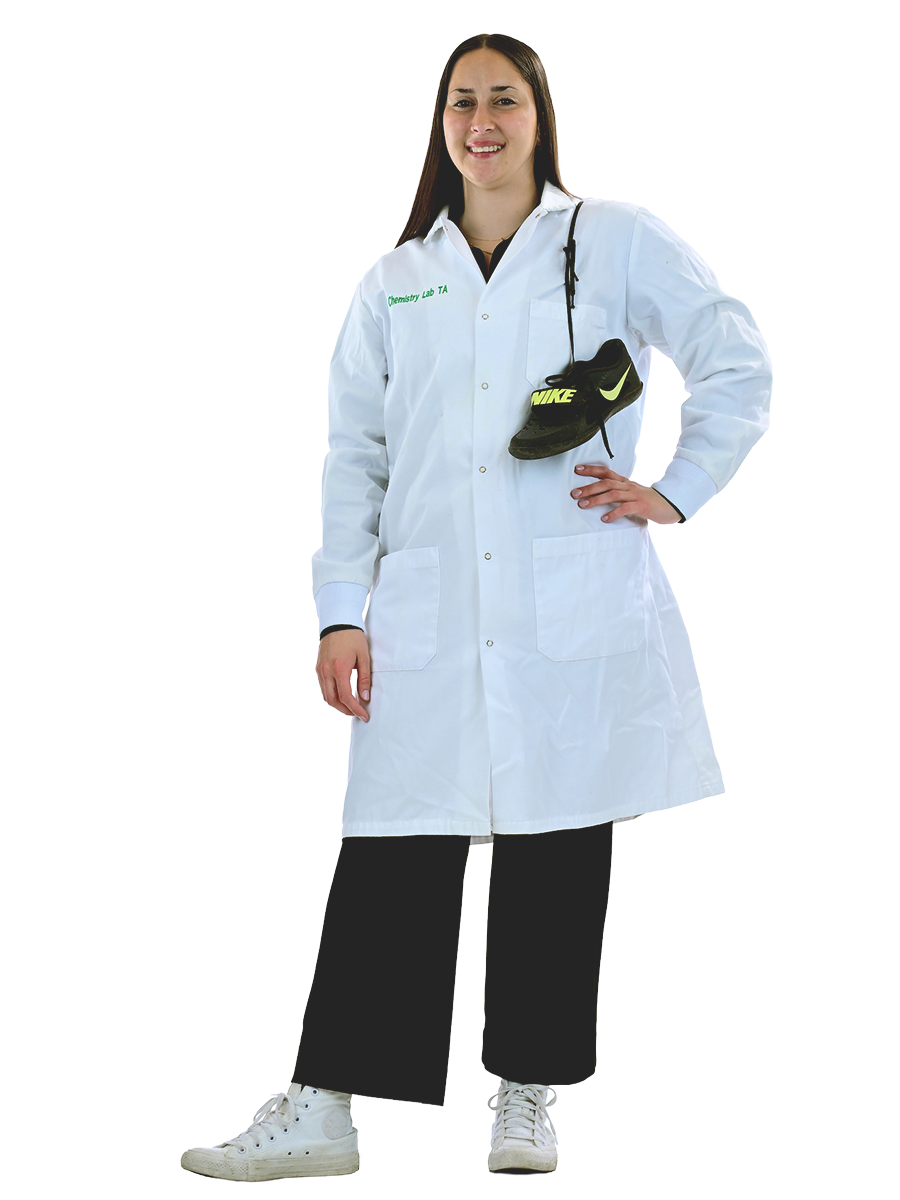 A female student stands wearing a lab coat with track shoes strung over her shoulder.