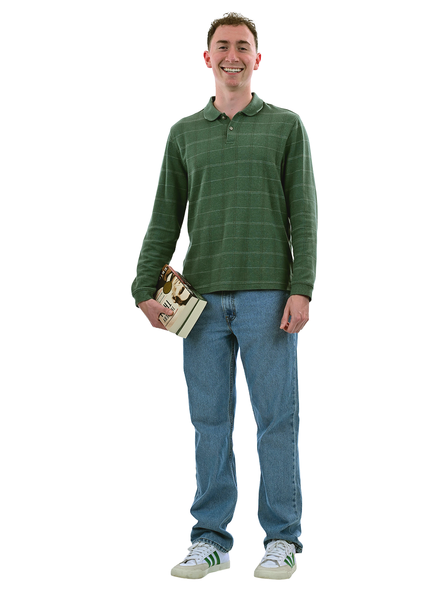 A male student in a green shirt and jeans stands holding books.