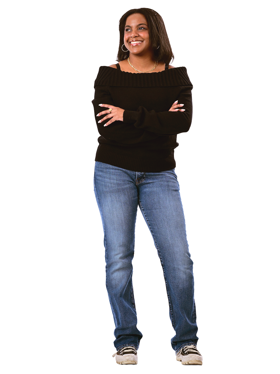 A female student in a black sweater and jeans stands with her arms crossed.