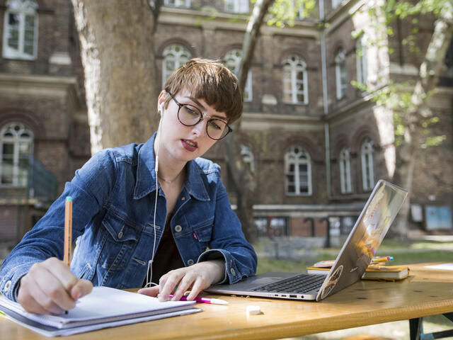 Student writing in notebook outside of Budapest campus.