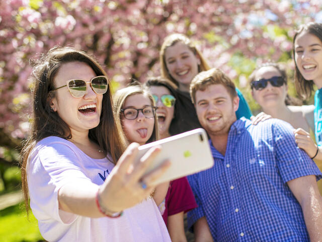 Students taking group selfie outside on campus.