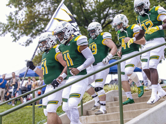 Football players coming down steps to the football field.