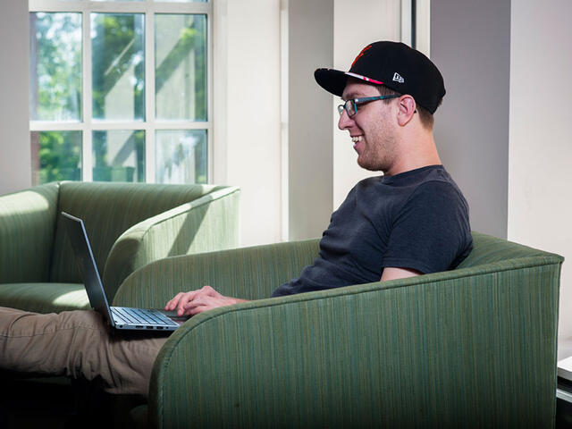 Grad student on computer in lobby.