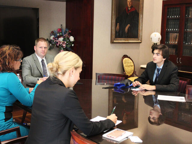 Student in business suit at conference table on Interviewing Day.